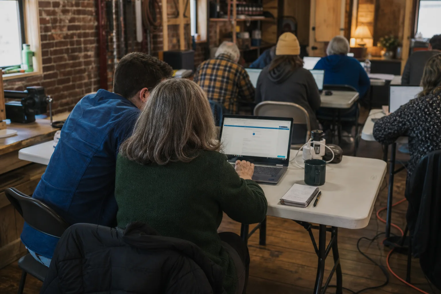 Neighbors working side by side on laptops in a small-town makerspace